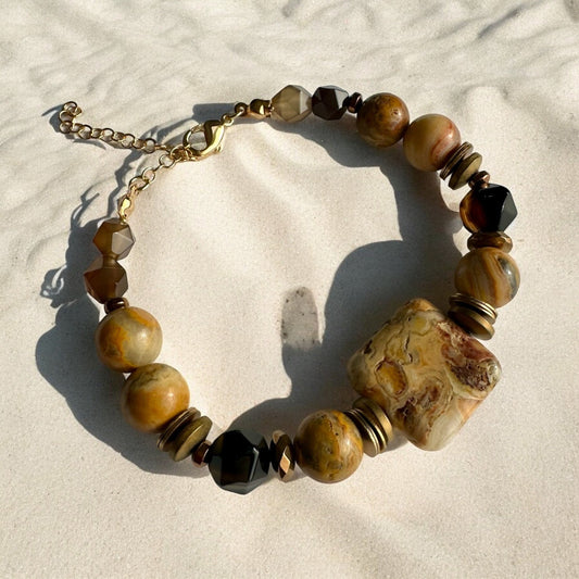 Crazy Lace Agate, Hematite, and Coffee Agate Crystal Bracelet on a sand