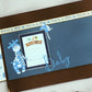 Flat lay of handmade A4 blue baby photo album with Maja design paper, bronze details and ribbon accents—customisable photo book for baby memories.
