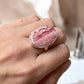 Rhodochrosite crystal ring on a finger