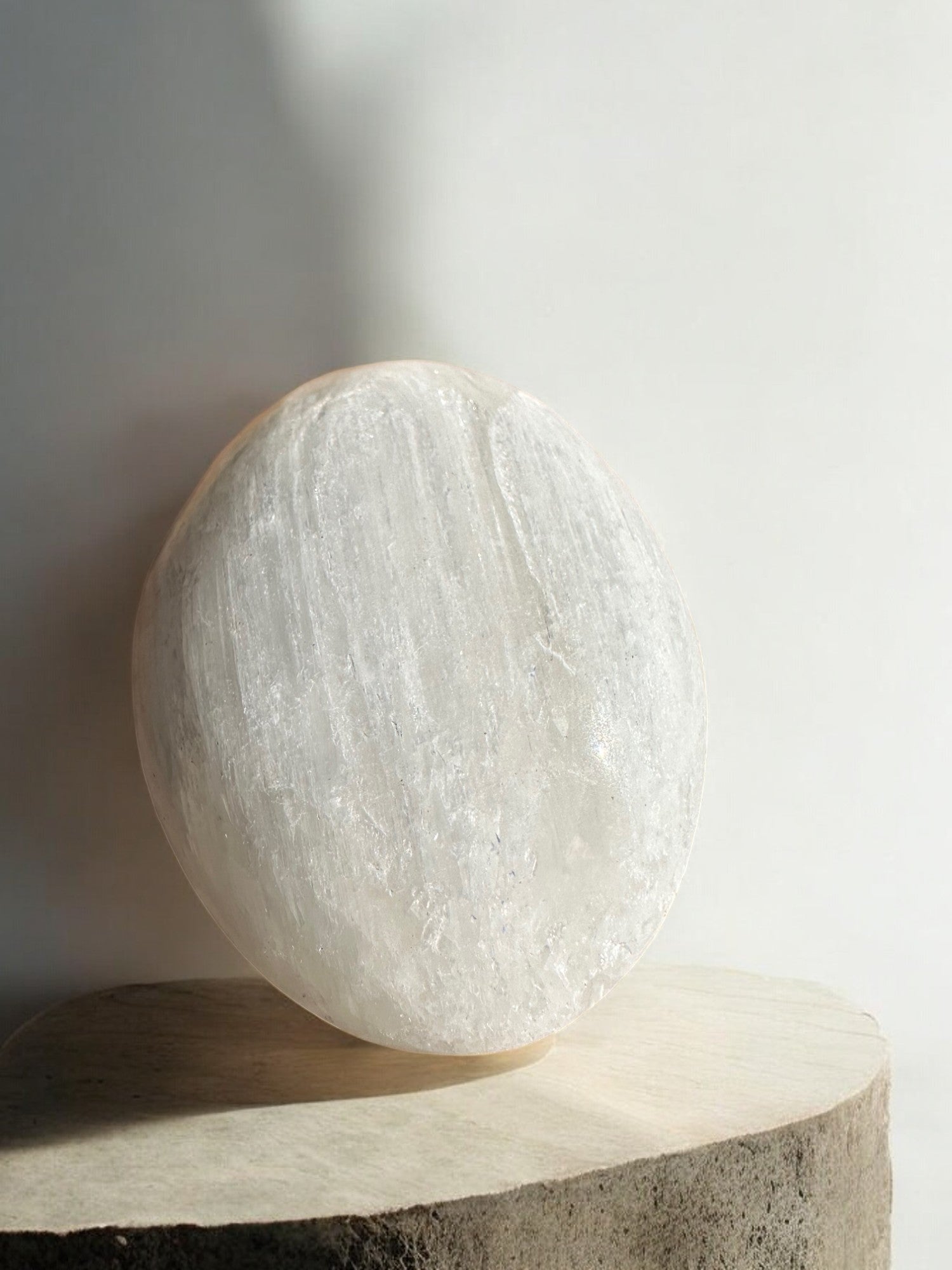 Selenite bigger palm stone against the wall