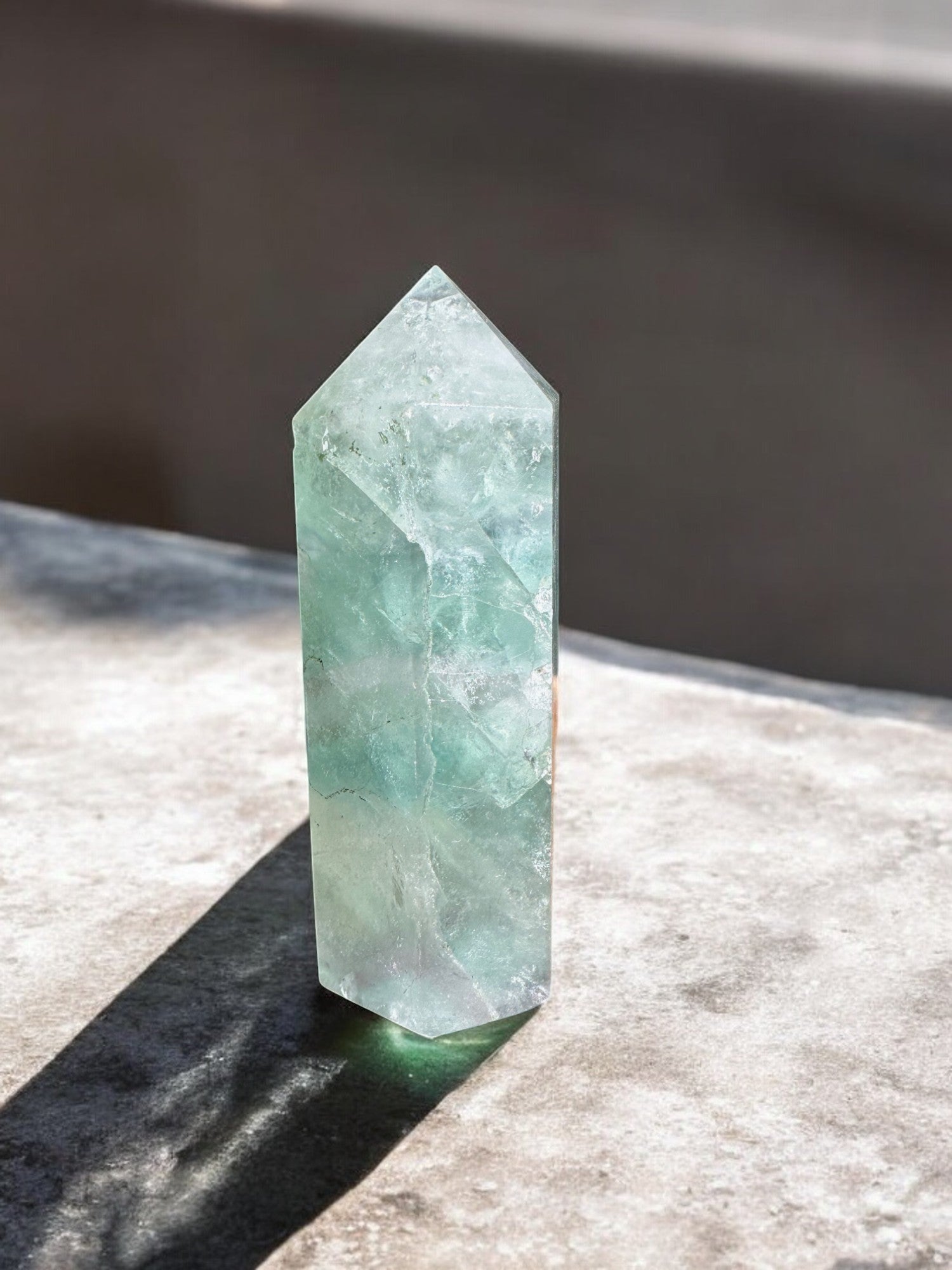 Green fluorite crystal tower on a concrete slab front view